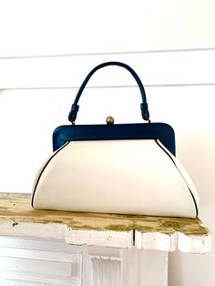 "Vintage vinyl spectator handbag. Extra large size. Little wear( photos show marks), clean interior, no Oder, strong clasp and handle.  The lean of the bag is an intentional design; not mis-shapen. The back is meant to lay flatter against the body. Pretty smart actually.  Measurements are approximate  Height 8\" not including clasp  Width 14\" Depth 4\" Strap drop 6\"" Vintage Blue Bag With Detachable Strap, Vintage Blue Shoulder Bag With Handles, Vintage Blue Top Handle Bag, White Retro Satchel With Detachable Strap, Retro Blue Bags For Formal Occasions, Retro Tote Satchel For Office, Retro Blue Evening Bags, Retro Office Satchel Tote, Blue Retro Evening Bag