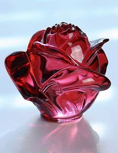 a red glass vase sitting on top of a white table