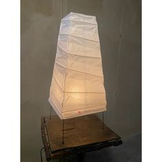 a white lamp sitting on top of a wooden table in front of a gray wall