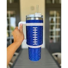 a hand holding a blue and white cup with a football on it