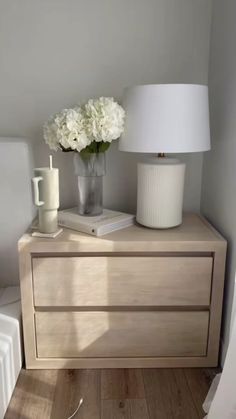 a nightstand with flowers and a lamp on it