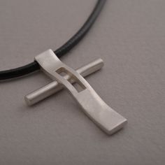 "Rejoice in your commitment to the faith with this modern cross necklace. Wear your Christianity with pride and show the world the beauty that lies within each time you get dressed. This modern cross necklace is custom handmade in majestic detail from sterling silver. Polished to a brilliant shine, it is suspended from a length of black leather cord to complete the look. It makes a fabulous gift and will be a heartwarming addition to his existing jewelry collection. Cross measures 3.4 cm x 2.5 c Modern Crucifix Cross Necklace As Gift, Modern Crucifix Necklace As Gift, Modern Cross Pendant Necklaces As Gift, Modern Necklaces With Cross Pendant For Gift, Modern Necklaces With Cross Pendant As Gift, Modern Stainless Steel Cross Necklace For Gift, Modern Cross Necklace As A Gift, Modern Cross Jewelry For Gift, Modern Silver Cross Pendant Necklace