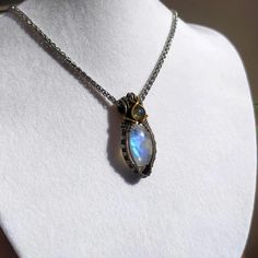 Elevate your style with this stunning handcrafted wire wrapped necklace featuring a shimmering blue Moonstone and a petite green Labradorite. The intricate wire wrapping is crafted using German silver and brass wire, adding a touch of elegance to the design. Measuring approximately 2x4 cm, this necklace hangs beautifully on a silver snake chain, creating a chic and timeless look. It makes a perfect gift for Mother's Day or any special occasion. Ready to ship with free shipping included. Materials: - Blue Moonstone - Green Labradorite - German Silver Wire - Brass Wire - Silver Snake Chain 45 cm  Dimensions: Pendant Size: Approximately 2x4 cm Blue Moonstone Wire Wrapped Necklace, Wire Wrapped Moonstone Jewelry For Jewelry Making, Wire Wrapped Labradorite Crystal Pendant Necklace, Artisan Wire Wrapped Crystal Pendant Necklaces, Artisan Wire Wrapped Pendant Crystal Necklaces, Artisan Wire Wrapped Crystal Pendant Necklace, Silver Labradorite Wire Wrapped Crystal Necklace, Wear Necklaces, Blue Moonstone