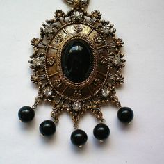 This fabulous Celebrity Gems medallion pendant necklace has a large black oval cabochon in the center with gold tone metal frame and eight sparkling clear rhinestones at the edge of the frame.  There are five round black plastic beads hanging from the medallion.  The medallion is 3 by 2½ inches and is suspended from a 21 inch thick double link gold tone chain.  The medallion is marked Celebrity Gems on the back and is in excellent condition. Thanks for looking and visiting my shop. Jewelry items may be combined for shipping discounts. Please view the shop often as I regularly add new and interesting items and offers are always considered. Vintage Oval Jeweled Necklaces, Vintage Jeweled Oval Necklace, Vintage Oval Jeweled Necklace, Large Pendant Necklace, Sarah Coventry, Shop Jewelry, Victorian Jewelry, Fantasy Jewelry, Plastic Beads