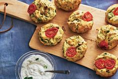 small muffins with tomatoes and spinach on a cutting board next to a bowl of yogurt