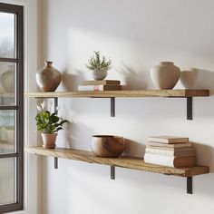 three wooden shelves with books and vases on them