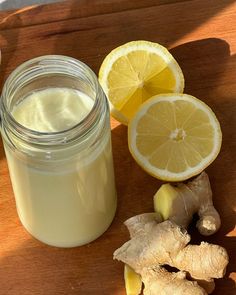 a jar of ginger juice next to sliced lemons and ginger