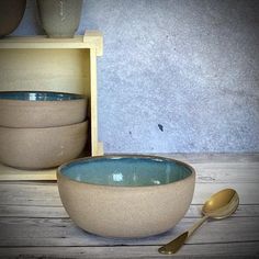 two bowls with spoons sitting next to each other in front of a box on a wooden table