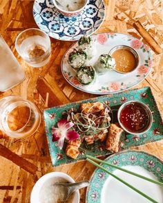 plates with food on them sitting on a table next to cups and saucers filled with condiments