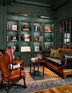 a living room filled with lots of furniture and bookshelves in green painted walls