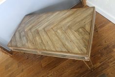 a wooden table sitting on top of a hard wood floor next to a white wall