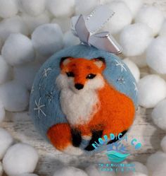 a felt fox ornament hanging from a ball of white cotton balls on a wooden surface