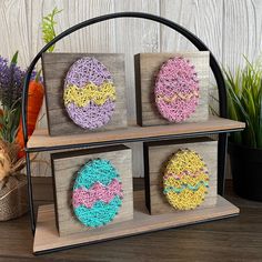 three wooden boxes with crocheted designs on them sitting on a table next to some plants