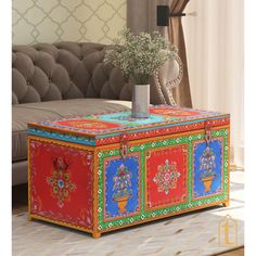 a colorful box with flowers in it sits on the floor next to a couch and window