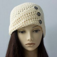 a mannequin head wearing a white crochet hat with buttons on it