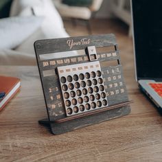 a desk with a wooden calendar sitting on top of it next to a laptop computer