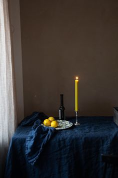 a plate with lemons on it next to a candle