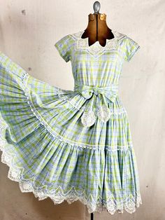 An authentic vintage patio or square dancing dress by Pom Pom Fashions label. a classic swing dress with a gathered and tiered full circle skirt. lace and ric rac trim. woven fabric. included matching sash tie belt. elastic waistband for comfort! era : 1950s material : cotton color : sky blue, lime condition : great, appropriate signs of age and wear as seen in photos size : approx xsmall to small , please compare measurements below shown on form with 36 chest - 26 waist actual garment measurements : chest : 36" shoulder : 15" arm : 12" around  waist : up to 30" skirt length: 26" total length : 41" - - - - - - - - - - - - - - - - - - - - - - - - - - - - - - - - - - - - - - - -  INTERNATIONAL SHIPPING AVAILABLE UPON REQUEST Craft Union does NOT accept returns or exchanges, all items are FIN Square Dancing Dresses, Vintage Tiered Dress With Lace Trim, Vintage Tiered Lace Trim Dresses, Retro Lace Vintage Dress With Ruffles, Vintage Terrarium, 1950s Western, Square Dance Dress, Pom Pom Fashion, Square Dance Dresses