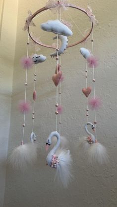 a mobile that has some kind of animal on it with feathers hanging from the ceiling