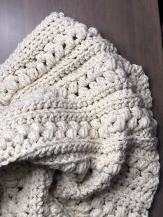 a white crocheted blanket laying on top of a wooden table