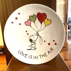 a plate with a snoopy dog holding balloons that say love is in the air