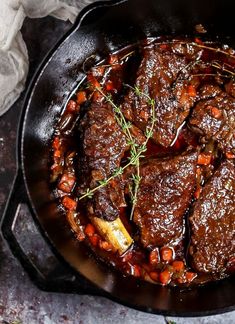 beef stew in a cast iron skillet with garnishes