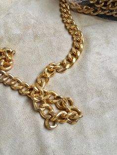 24x16 mm curb metal chain with a shiny, metallic gold finish. This iron chain features closely-knit linked chains that have subtle distresses carved into the metal Brass Chain Link Bracelet With Gold Chain Detail, Brass Gold Chain Link Bracelet, Metal Cuban Link Chain Necklace, Gold Chain Link Ring Made Of Metal, Gold Metal Chain Link Ring, Gold Chunky Chain Bracelet In Brass, Metal Curb Chain Necklace, Gold Metal Chain Ring, Gold Cuban Link Chain Necklace