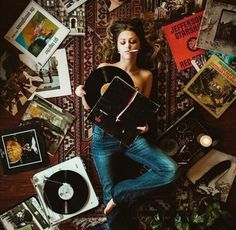 a woman laying on top of a wooden floor next to a record player and various other items