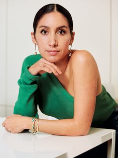 a woman sitting at a table with her hand on her chin and looking off to the side