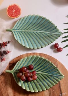 two plates with grapefruits on them next to an orange and palm leaf