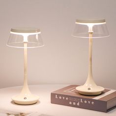 two lamps sitting on top of a table next to a book