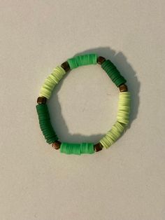 a green and brown beaded bracelet on a white surface