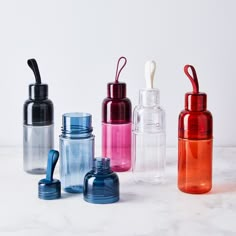 several different colored glass bottles with toothbrushes in them on a marble surface,