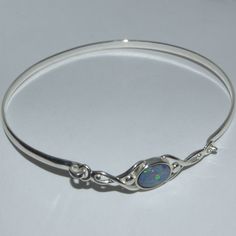 Silver and Opal Celtic style bracelet 925 silver bracelet of D shape profile with Opal cabochon set in a Celtic connector, suitable for wrist size up to approximately 7 to 7.5 inches (small/medium).     * Australian Opal oval cabochon 8mm x 6mm      * Connector length: 33mm approximately     * Internal diameter: 64mm The traditional birthstone for October, Opal is said to reflect the thoughts of the wearer, increasing emotions. To look after your Opal, clean with a soft, untreated cloth and mild soapy water, taking care not to submerge the gemstone in soapy water. Gently pat dry and be sure jewellery is completely dry before storing. Measuring 5.5-6.5 on the Gem hardness scale (Diamond being 10), it is recommended that your Opal ring is stored away from other pieces of jewellery as metals Celtic Style, 925 Silver Bracelet, Australian Opal, Oval Cabochon, Opal Rings, Silver Bracelets, Fashion Bracelets, Jewelry Inspiration, Bangle Bracelets