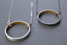 A simple circle with a secret inside.  A wide band of sterling silver has been formed into a circle and the inside coated with 23k yellow gold leaf.  Circle is 4 mm thick and the diameter of the circle is around 1 inch.  Securely attached to sterling silver curb chain with wired headpins.  Oxidized or bright finish available.  16 or 18 inch length.Gold leaf has been sealed with a clear varnish to protect the finish.Add the matching earrings to complete the look- https://www.etsy.com/listing/4677 Modern Silver Necklace, Eternity Necklace, Interlocking Circle Necklace, Keum Boo, Gold Circle Necklace, Minimalist Earrings Gold, Cube Necklace, Karma Necklace, Stick Earrings