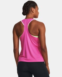 a woman in pink tank top and black leggings looking at the back of her body