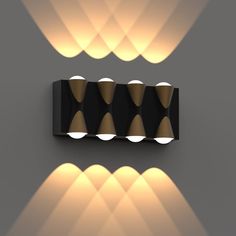 a black and white wall light with three lights on it's sides, in front of a mirror