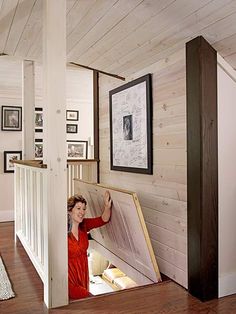 a woman standing in the doorway of a room with pictures on the wall and stairs