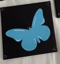 a blue butterfly sitting on top of a black surface next to some pens and paper