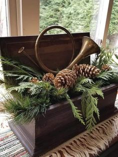 a wooden box filled with pine cones and greenery