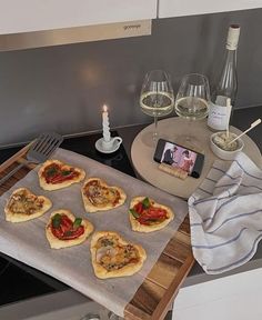 small pizzas sitting on top of a metal tray next to wine glasses and a cell phone