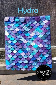 a blue and purple mermaid scale quilt with the words hydra written in front of it