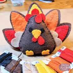 a stuffed turkey sitting on top of a table next to some knitting needles and yarn