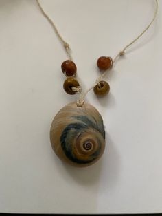 a necklace with two beads and a shell on the front is hanging from a string