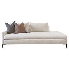 a white couch with some pillows on it's back and one pillow in the middle