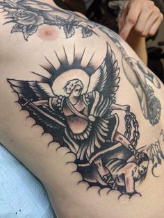 a tattoo on the back of a woman's thigh with an angel and cross