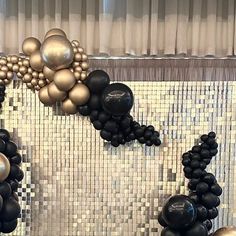 black and gold balloons are hanging on the wall