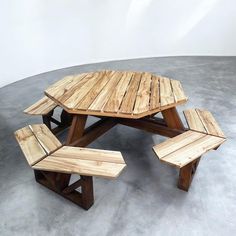 a wooden table and bench made out of wood planks on concrete flooring with white walls in the background