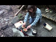 a woman is cooking food over an open fire