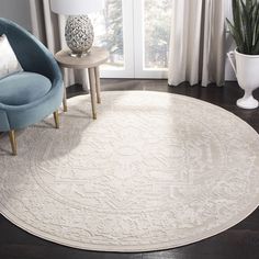 a large white rug in a living room with a blue chair and potted plant